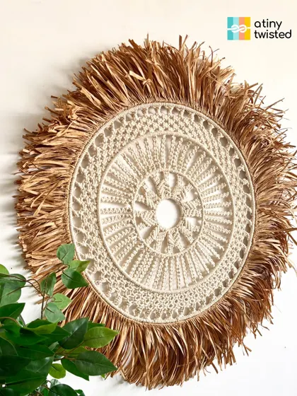 This large, round wall hanging features a detailed macramé mandala at its center, framed by a beautiful, wild raffia fringe. It's a true celebration of natural materials and handmade artistry.