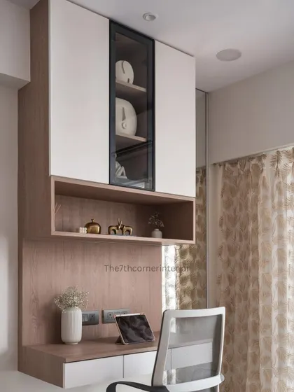 A study and workspace from a 3BHK project, featuring ample overhead storage with a glass-shuttered niche to display decor. The design is both highly functional and aesthetically pleasing.