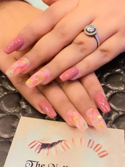 A lovely set of long, square nails in a dusty rose color. The accent nails feature a subtle, abstract design with small star glitter for a touch of whimsy.