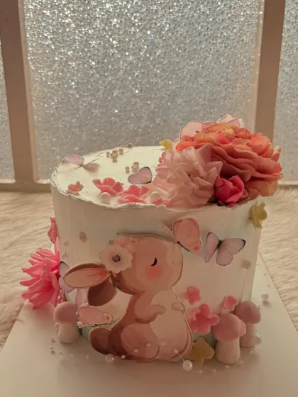 A sweet and soft baby shower cake. The design features a cute bunny, fresh flowers, and delicate butterflies in a gentle color palette.