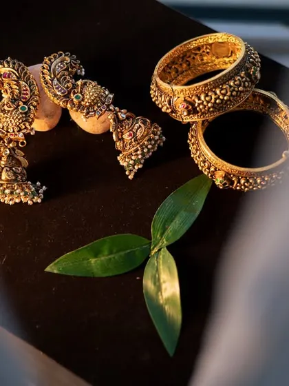 A detail shot of the traditional gold jewelry, including jhumkas and bangles, beautifully arranged for the Seemantha ceremony.