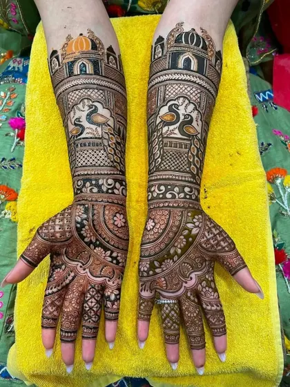 This stunning bridal design features peacocks looking out from architectural jharokhas (windows). The colors of the client's outfit make the henna pop.