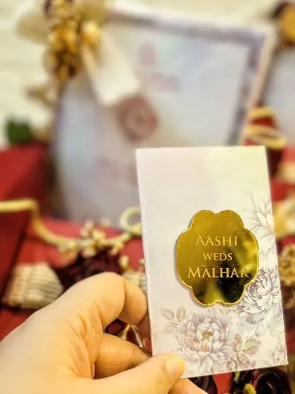 The first card presentation is a cherished tradition. For this invite, I used a classic red and gold theme to symbolize love and celebration, with a personalized acrylic tag for the couple, Aashi and Malhar.