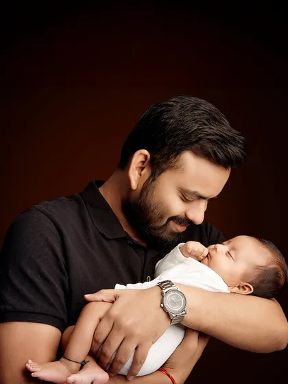 A father's gentle gaze at his sleeping newborn. This portrait captures the quiet strength and deep love of a new dad.