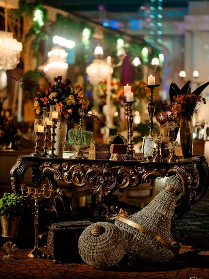 A beautifully chaotic arrangement of decorative items, including a fallen chandelier, candelabras, and floral arrangements, evoking the feeling of a beautifully preserved ruin.