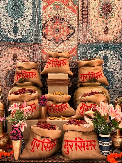 A creative installation for a Turkish market theme, using spice-filled jute bags with the couple's names printed in Hindi, set against a wall of colorful carpets.