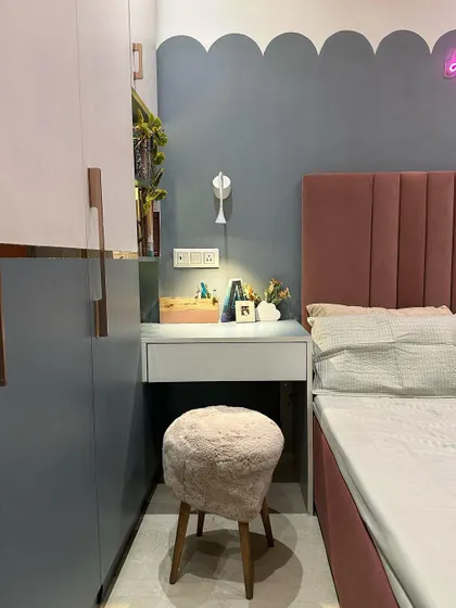 The study-cum-dressing table in this bedroom is lit by a modern wall sconce, providing focused light for reading or getting ready.