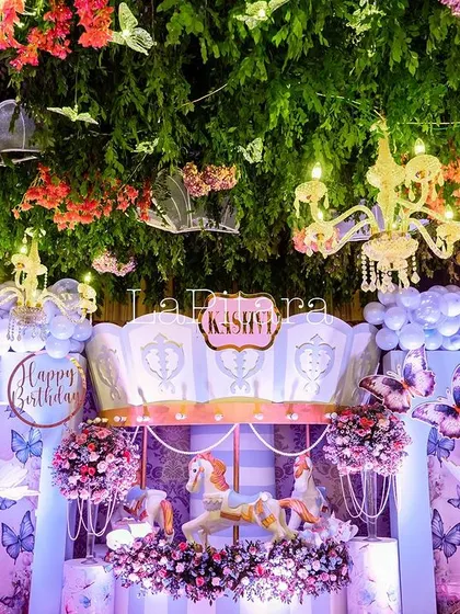 The carousel centerpiece viewed from below, showing the magical ceiling treatment with hanging greenery, chandeliers, and butterflies.