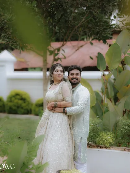 A classic couple portrait in a garden, with the groom-to-be embracing his partner from behind.