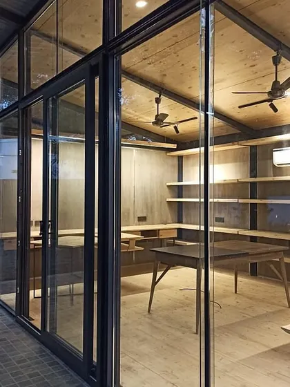 An exterior view of the Gazebo 1.0 modular office, showing how the glass facade connects the interior to the outdoors. This lightweight steel structure is designed for flexibility and can be easily assembled or disassembled as needed.