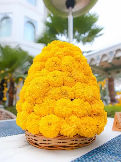 A tabletop centerpiece for a Haldi, featuring a large arrangement of marigolds in a wicker basket.