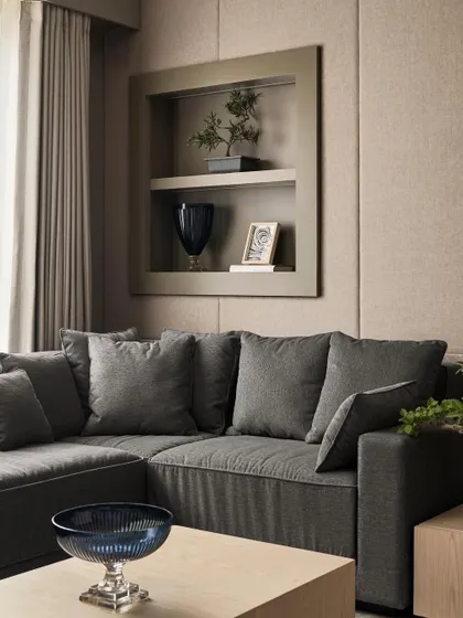 A detail of the cozy sitting corner in the multifunctional guest room. A plush L-shaped sofa and a recessed display niche create a comfortable spot for the family to relax.