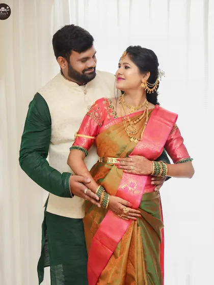 A beautiful portrait of the expecting couple, taken during their baby shower. They are dressed in festive traditional wear, smiling at each other, surrounded by the joy of the day.