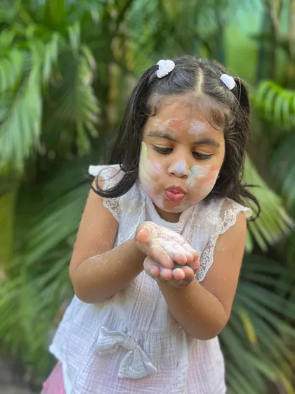 Blowing away the colorful, natural clay powder. It's a playful and safe way to enjoy the festival of colors.