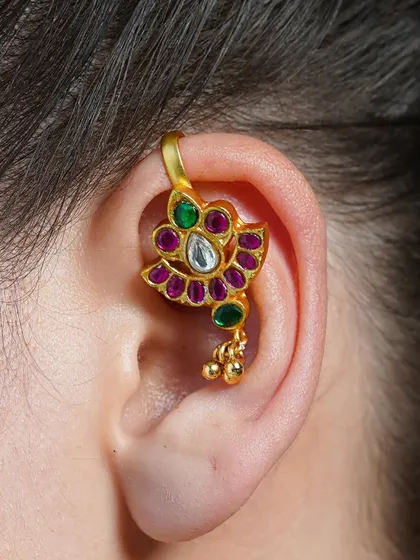 A close-up of our Alayaa earcuff, showcasing the intricate setting of polki, ruby, and emerald stones in a floral design.