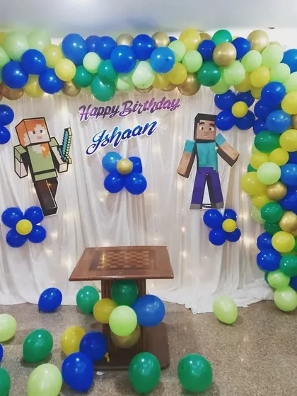 A fantastic Minecraft-themed birthday backdrop for Ishaan. We created this fun setup with a custom balloon arch in blue, green, and gold, complete with character cutouts to bring the popular game to life.