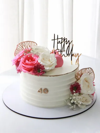 A simple yet beautiful 40th birthday cake. The textured white ganache is adorned with fresh flowers and rose gold accents for a modern and chic look.