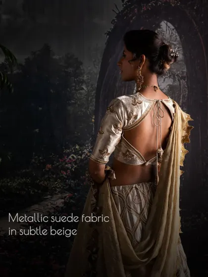 The back of this metallic suede lehenga in subtle beige features a deep, alluring cut, designed to create a memorable and graceful silhouette for the modern bride.