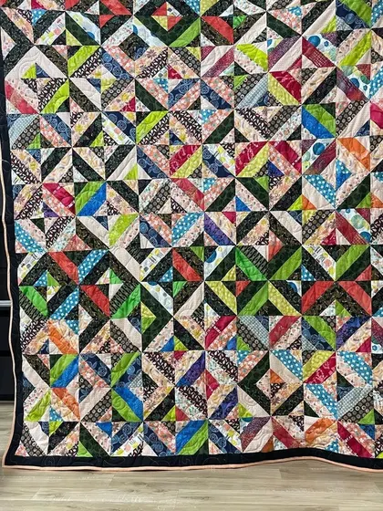 A scrappy and modern quilt with a complex geometric pattern, using a multitude of colorful fabrics.