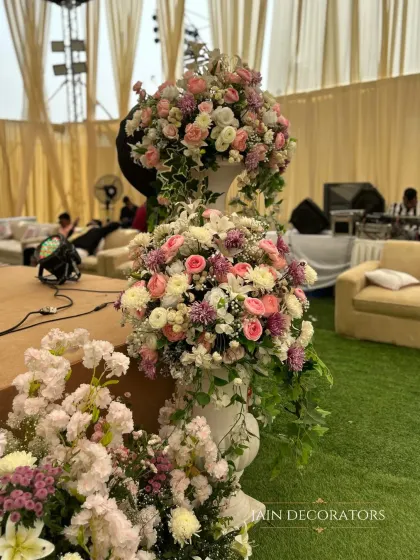 A tower of pastel perfection. These tiered floral arrangements in classic white urns add a touch of timeless elegance and romance to the wedding decor.