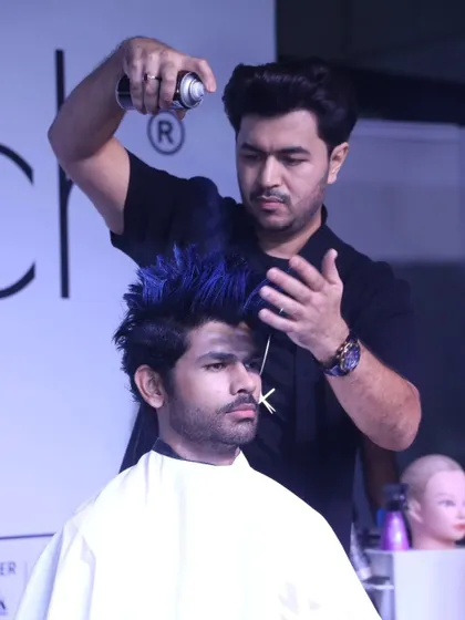 The final touches on a live hair styling demonstration. Using hairspray to lock in the volume and texture of this creative men's style.