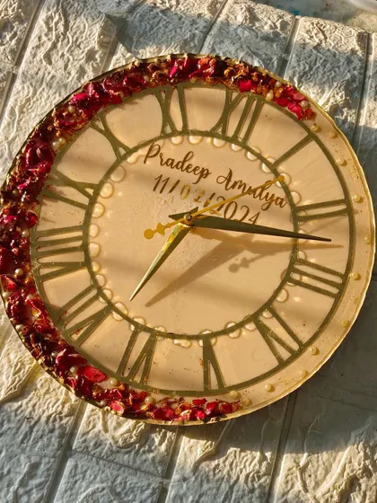 This elegant clock has a simple design with a border of preserved red rose petals on a cream-colored background. The large, classic clock face makes it easy to read.
