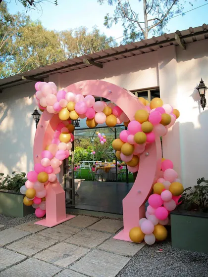 A festive balloon arch at the entrance of The Backyard for a birthday party. The bright pink and gold balloons create a cheerful and celebratory mood.