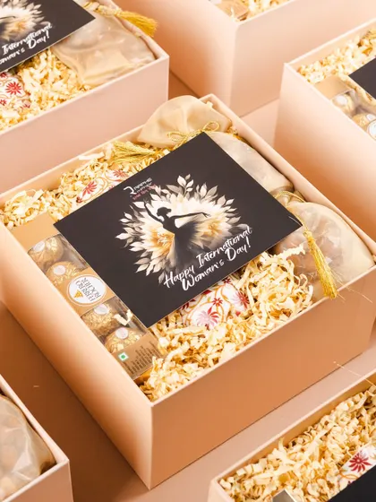 The inside of the RAPHE Women's Day hamper, filled with indulgent treats like Ferrero Rocher chocolates and premium dry fruits in elegant potlis.