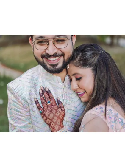 A happy, relaxed portrait of the couple. The bride's hand, adorned with mehndi and her engagement ring, is a beautiful focal point.