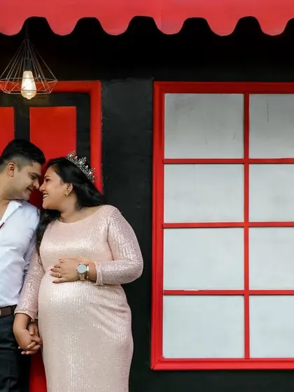 This is a duplicate of image 2, showing an intimate moment between an expecting couple. It is captured against one of the modern, vibrant backdrops at our Bangalore studio.