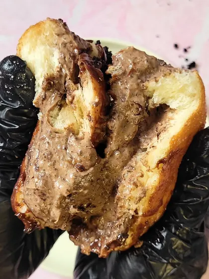 A closer look at the indulgent filling of the Bad Boy Bombolini. You can see the rich chocolate cake crumbs mixed right into the creamy custard, creating a unique and unforgettable texture.