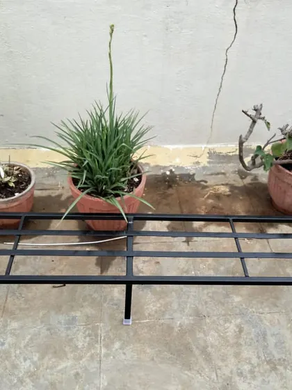 A simple yet effective solution for a few terrace pots. This long, single-tier stand keeps the plants off the ground, protecting the surface and giving the corner a more organized appearance.