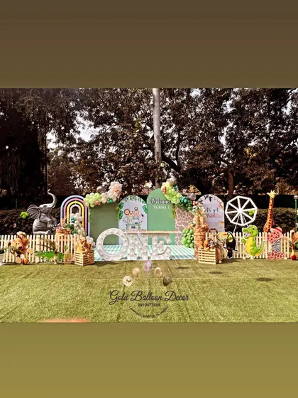 The main stage for an outdoor jungle party, featuring a mix of animal props, rainbow elements, and a large "ONE" sign.