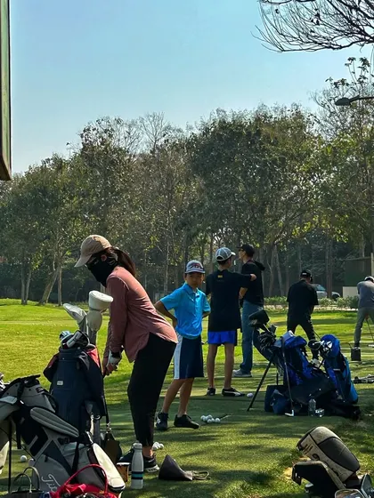 A group of young golfers and a female player enjoying their time at the range.