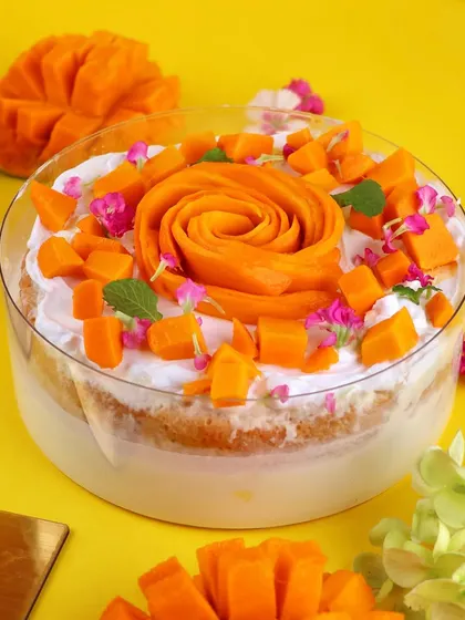 A beautiful shot of our Mango Tres Leches cake, decorated with a mango rose and edible flowers. It's sunshine in a slice.