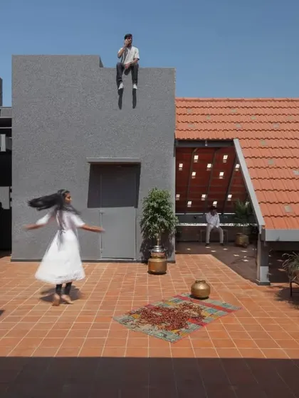 The terrace of the Madhura house is designed as a playground. The terracotta tiles provide a warm, earthy surface for relaxation and play, set against the backdrop of the sloping clay tile roof.