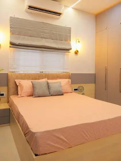 A calm and soothing bedroom with a neutral color palette. The combination of grey wall panels, a light wood bed frame, and a large plant creates a peaceful and natural ambiance.