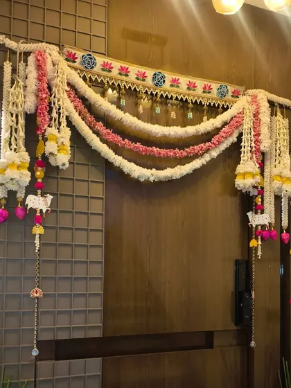 An ornate floral toran for a main door decoration during Diwali, made with artificial flowers, pearls, and decorative hangings.