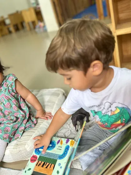 After a busy day, quiet moments are just as important as active play. This child is peacefully absorbed in a picture book in our reading corner, showing how I provide a calm space for individual exploration and a budding love for reading.