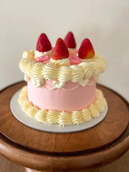 A sweet and simple vintage-style cake. This pink buttercream cake is decorated with classic piping, topped with fresh strawberries for a fresh and pretty look.
