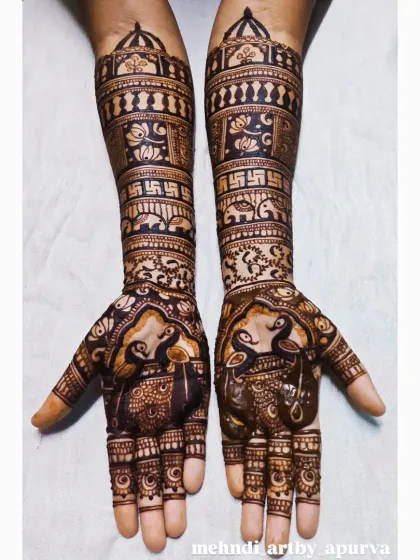 This intricate bridal henna showcases a blend of auspicious symbols. You can see graceful peacocks on the palms and the sacred swastika symbol on the forearms, all woven together with detailed filler patterns.