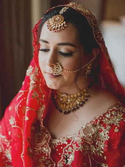 A close-up of our beautiful Punjabi bride. We chose a small, delicate nath and a classic tikka to complement her stunning red lehenga with intricate jaal embroidery.