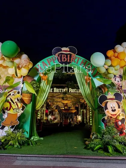The jungle safari entrance arch illuminated at night, creating a dramatic and inviting entryway for the birthday celebration.