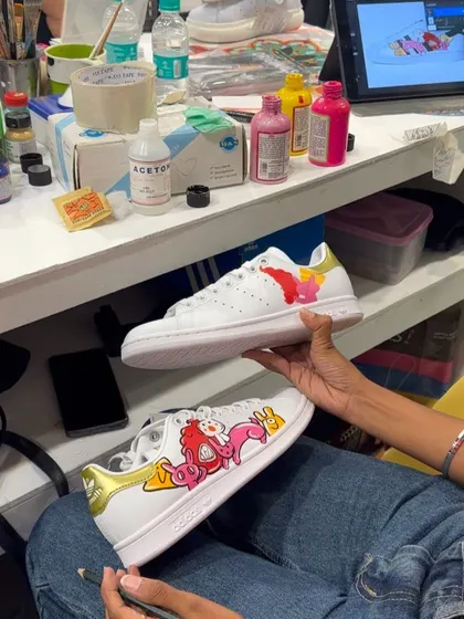 Here I am, bringing a digital design to life on a pair of Adidas Stan Smiths during a live customization event. You can see my iPad with the digital mockup right next to the actual hand-painted work.