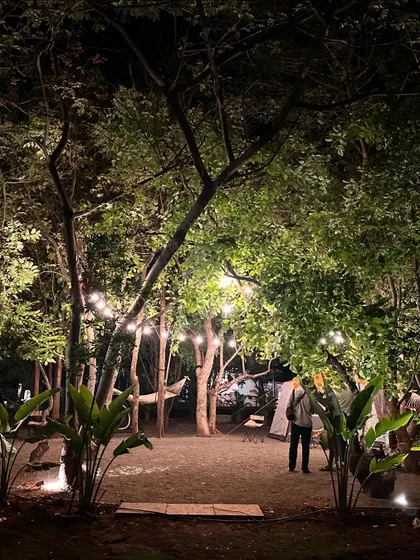 A wide view of our wooded camping area at night. The ambient lighting and scattered tents create a serene and secure environment for an overnight corporate retreat.