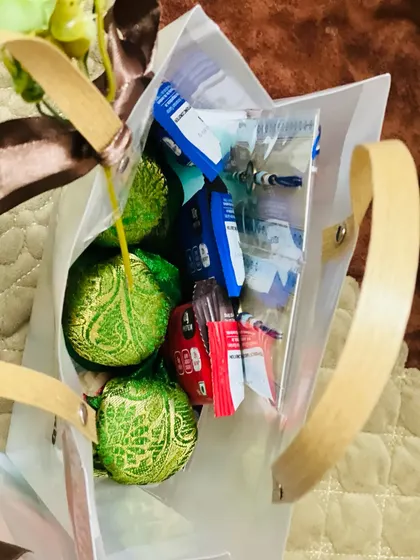 An overhead view of a Rakhi gift bag, showing the contents which include protein bars and traditionally wrapped sweets.