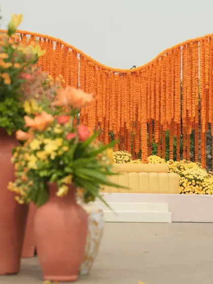 Another angle of the orange marigold Haldi stage, showing the terracotta vases with floral arrangements that complement the traditional theme.