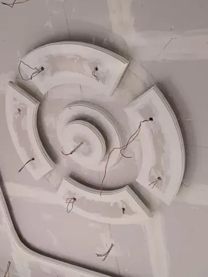 A circular POP design with curved segments, with wires indicating placement for numerous small spotlights to create a sparkling effect.
