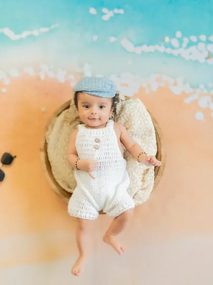 A day at the beach, right in the studio! This creative flat-lay setup with a sand-and-sea backdrop makes for a unique newborn portrait.
