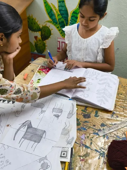 I'm providing one-on-one guidance to a young student working on a drawing inspired by Saura art. This personalized attention helps students understand complex patterns and compositions.